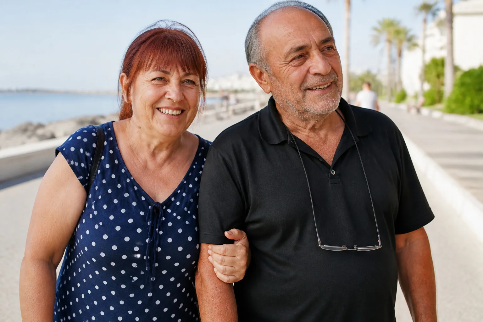 Sahil yolunda kol kola yürüyen, gülümseyen yaşlı bir çift